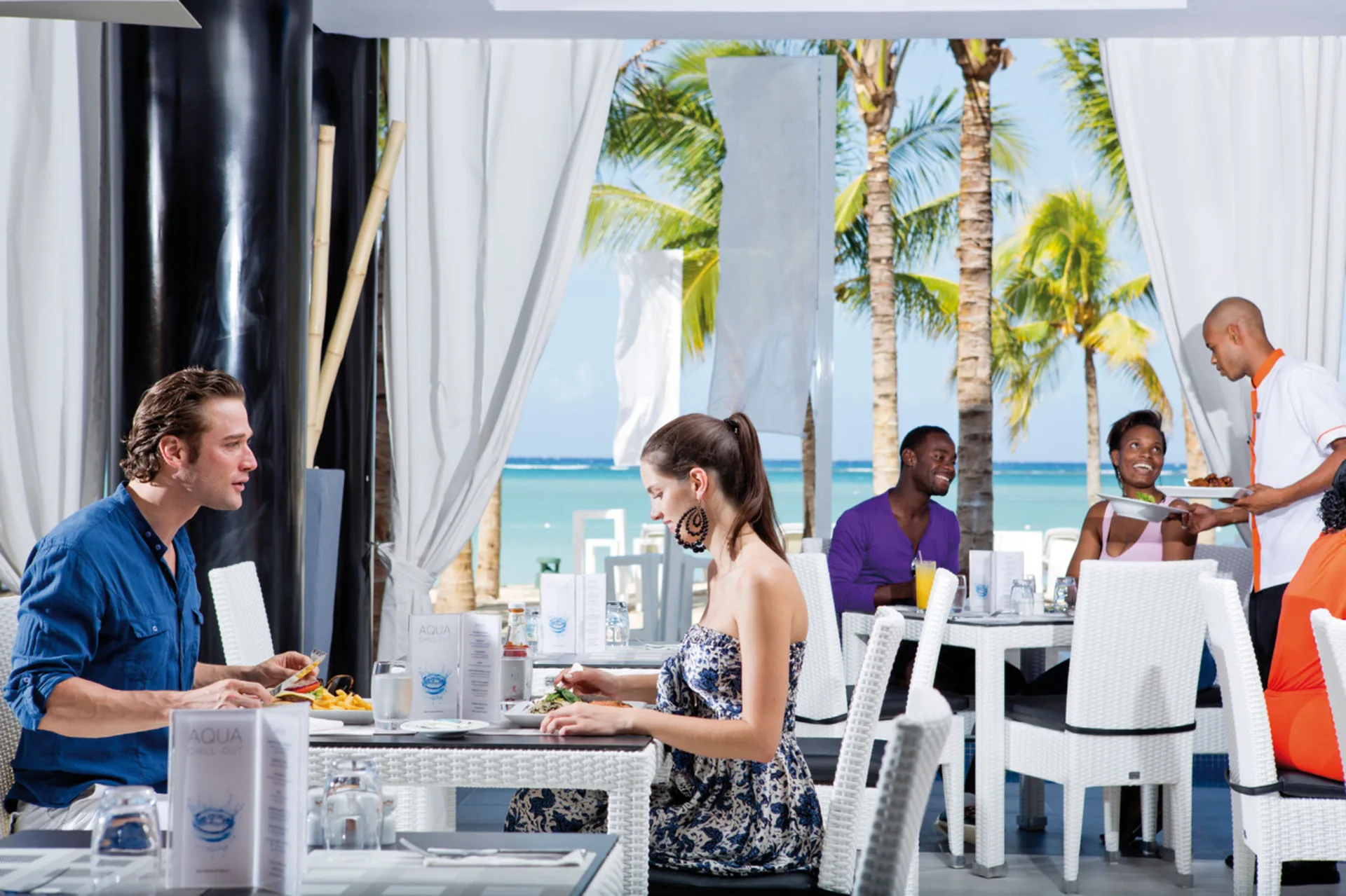 Guests dine in a bright beachside restaurant at Hotel Riu Palace Jamaica.
