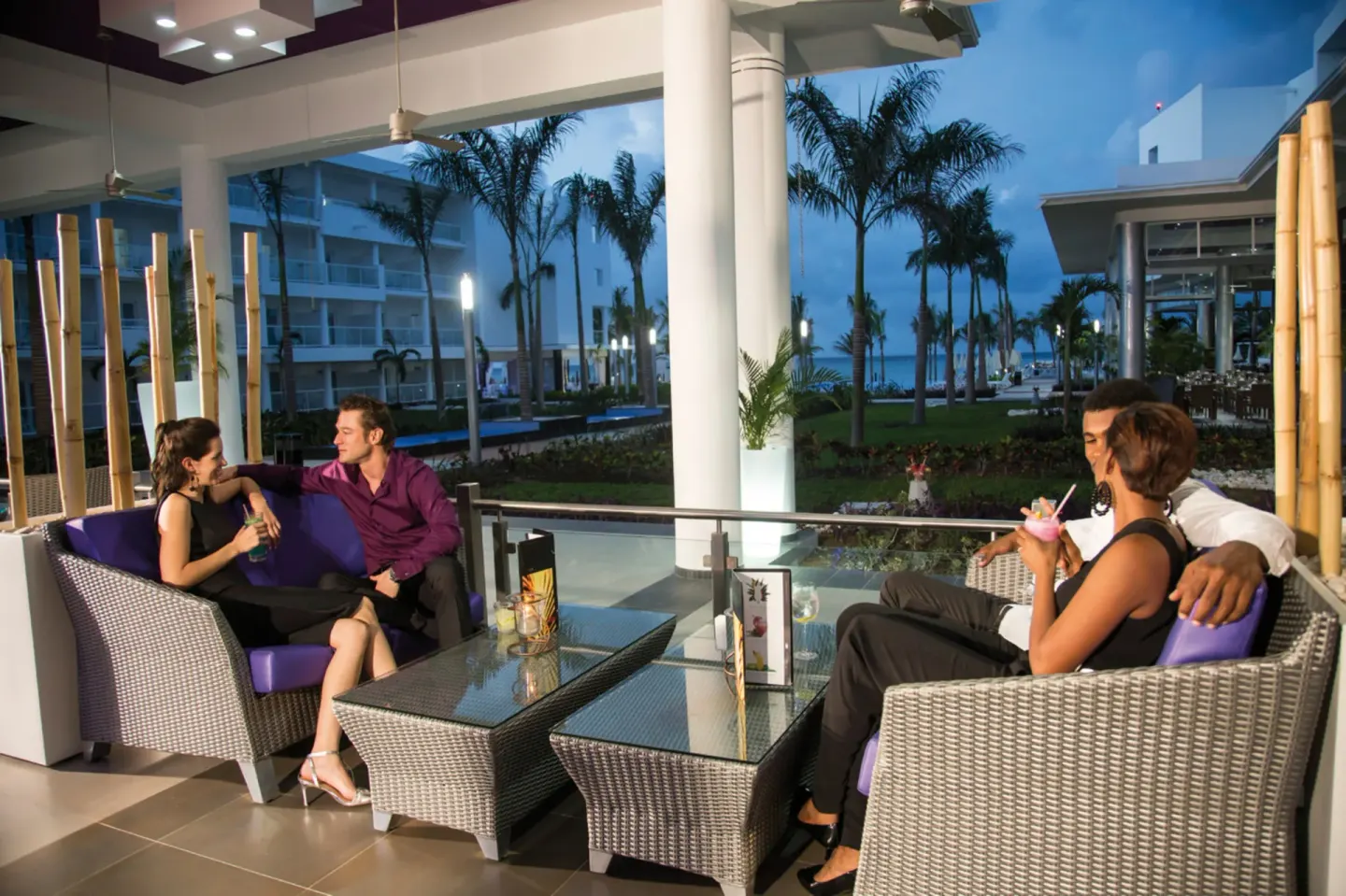 Guests lounge on a covered terrace at dusk at Hotel Riu Palace Jamaica.