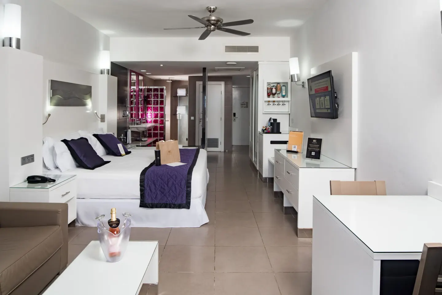Oceanfront Junior Suite with bed, lounge area, TV, and entry at Hotel Riu Palace Jamaica.