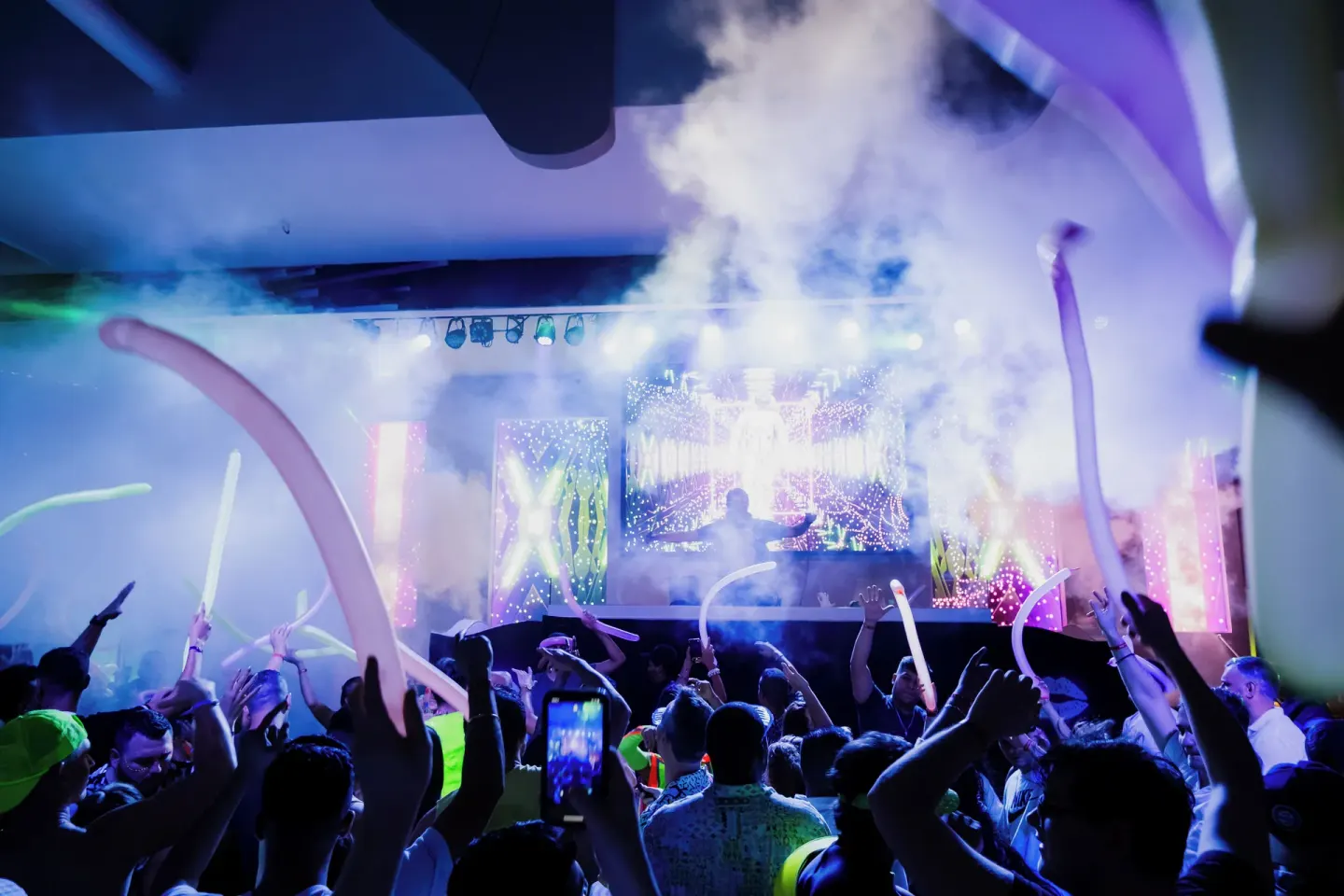 Crowd with glow balloons facing a DJ stage at Hotel Riu Palace Kukulkan.