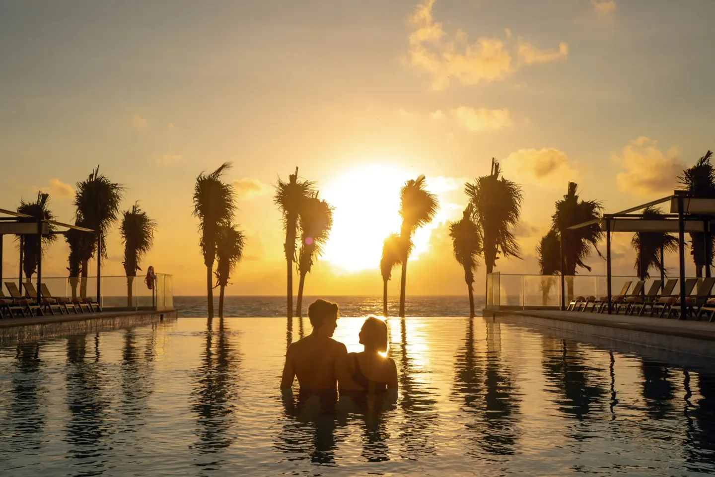 Couple in the infinity pool at sunset at Hotel Riu Palace Kukulkan.