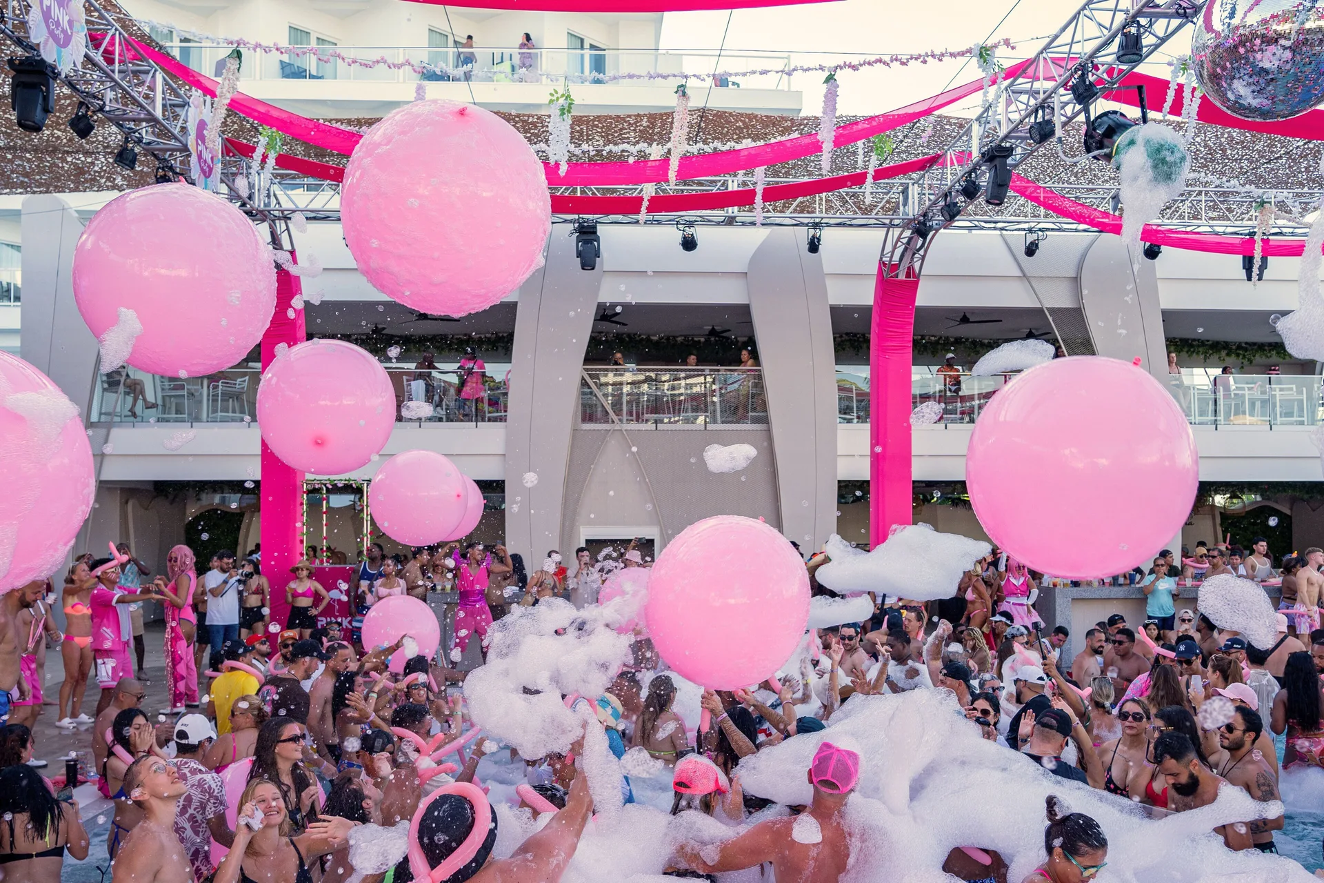Crowds toss pink beach balls during a foam pool party at Hotel Riu Palace Kukulkan.