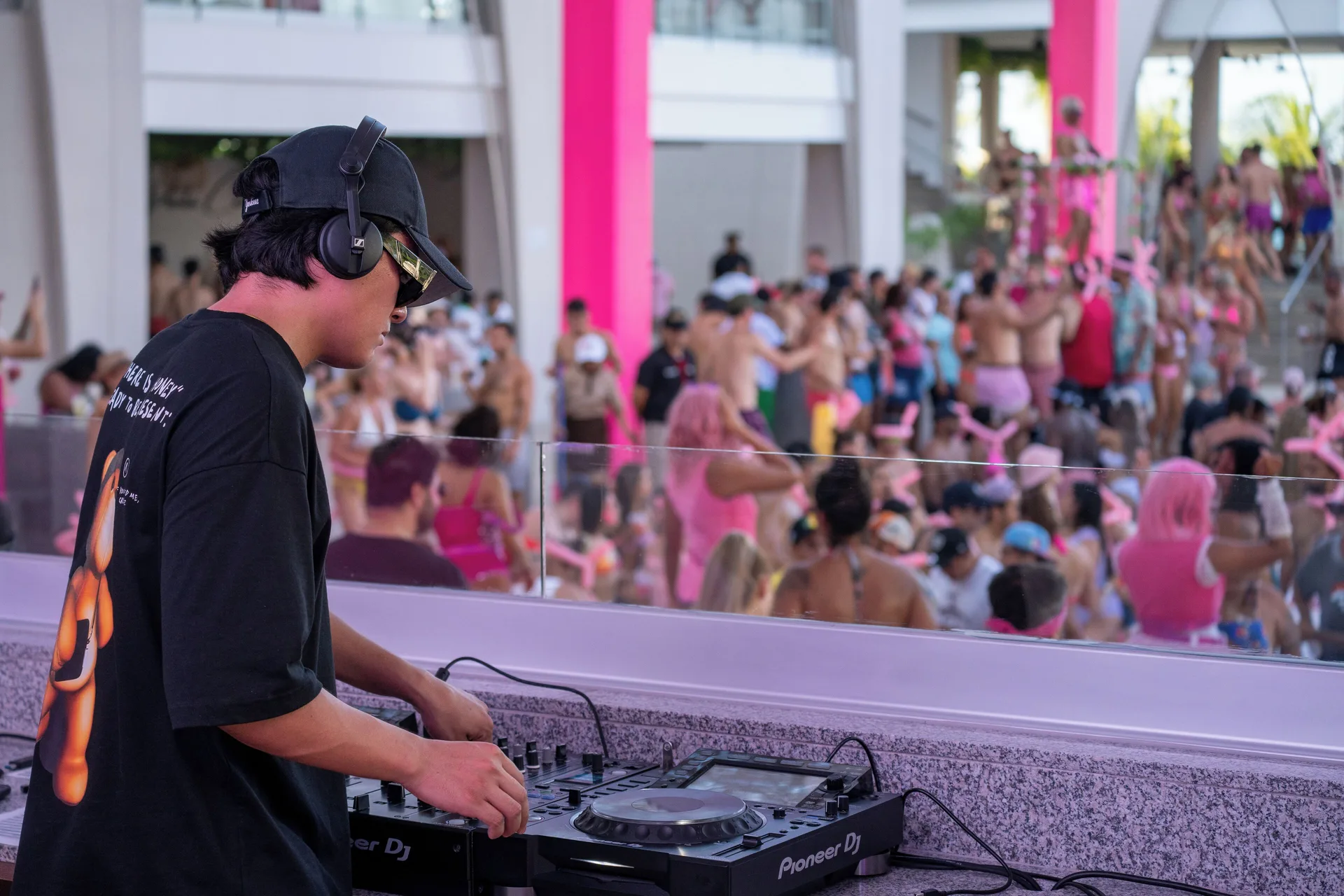 A DJ plays music for a crowded pool party at Hotel Riu Palace Kukulkan.