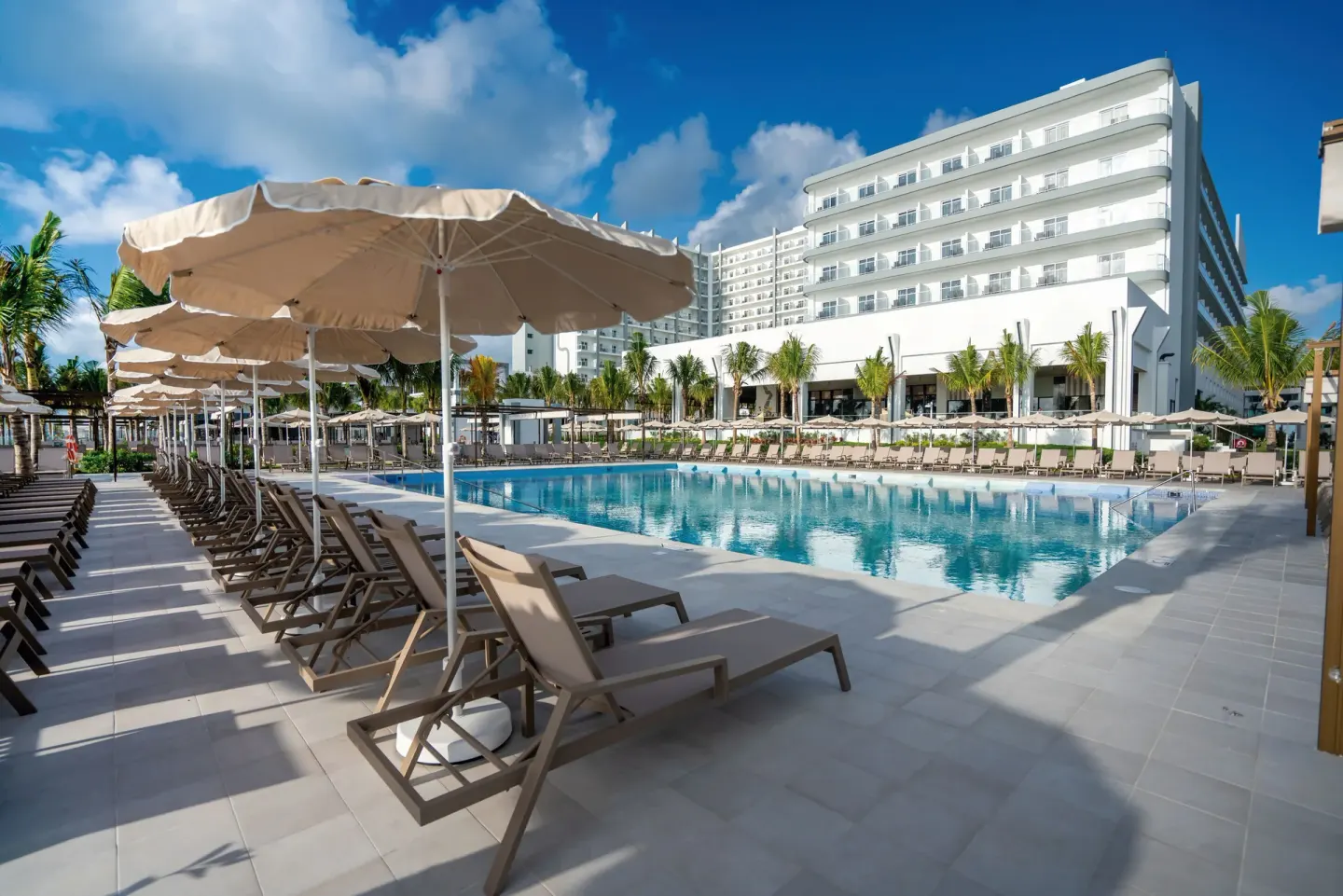 Pool terrace with umbrellas, loungers, and hotel balconies at Hotel Riu Palace Kukulkan.