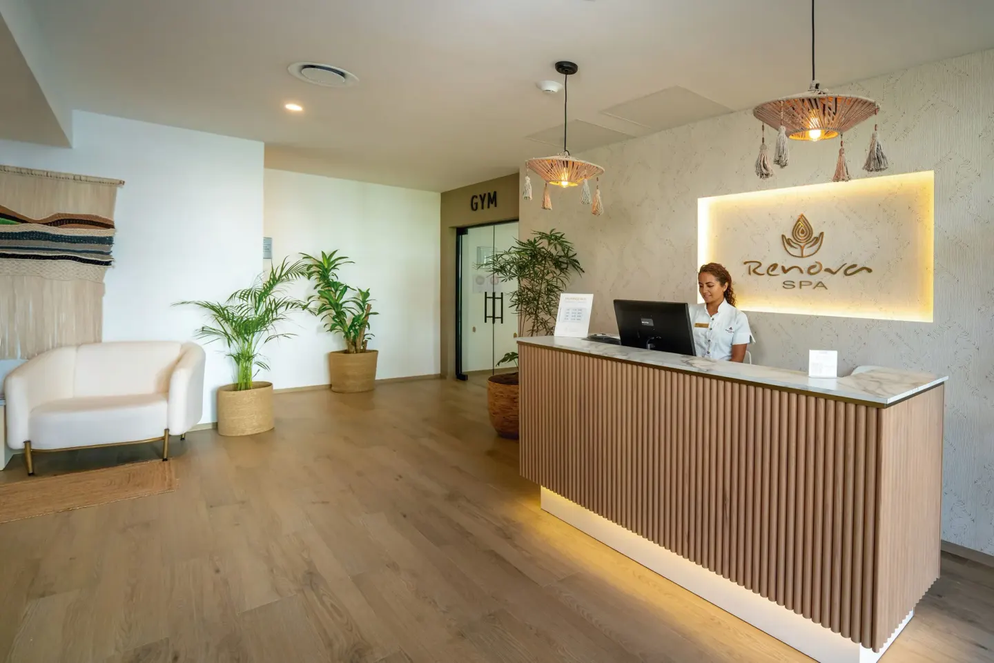Spa reception desk with plants and lounge seating at Hotel Riu Palace Kukulkan.