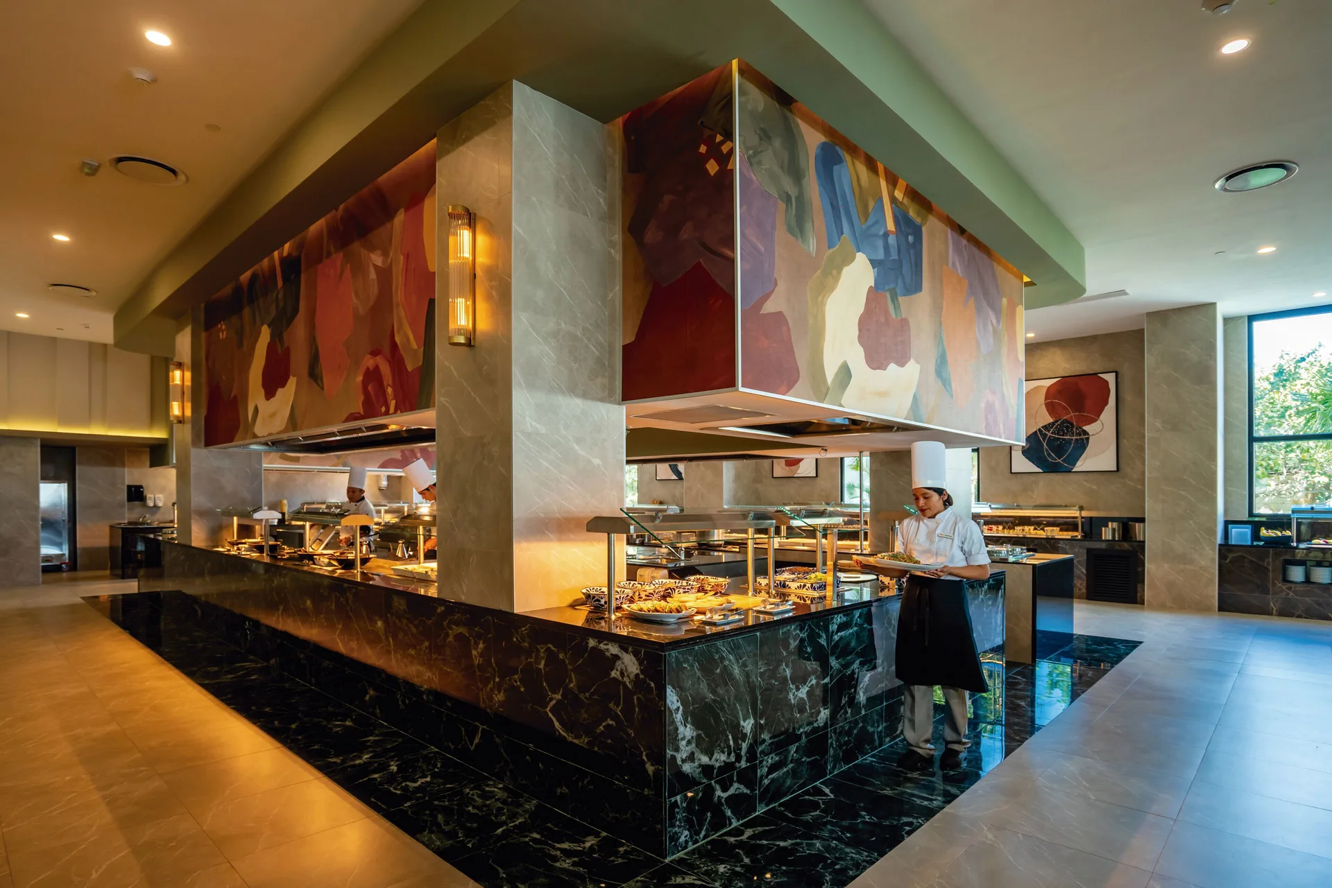 Large buffet island with chefs and food displays at Hotel Riu Palace Kukulkan.