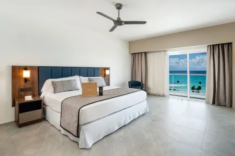 King bed and balcony doors with ocean view in an Elite Club Suite at Hotel Riu Palace Kukulkan.