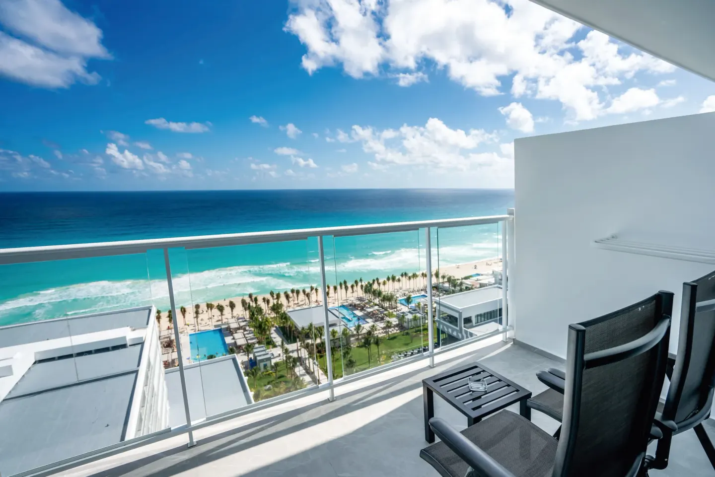Oceanfront balcony with chairs from a Junior Suite at Hotel Riu Palace Kukulkan.