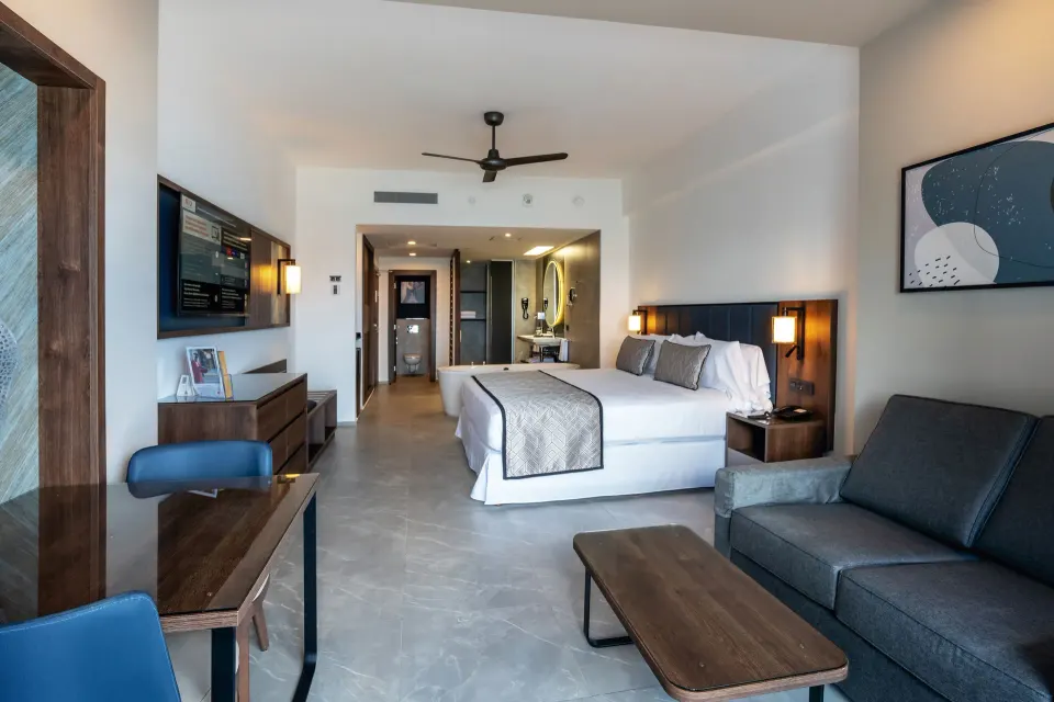 Junior Suite Ocean Front Elite Club with king bed and sitting area at Hotel Riu Palace Kukulkan.