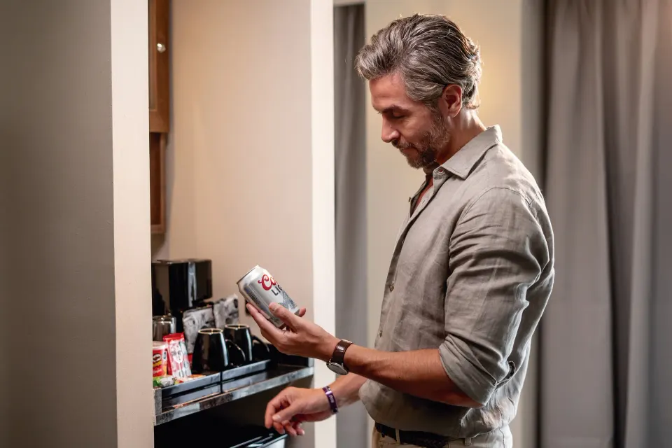 Guest selecting a canned drink from the in-room minibar at Hotel Riu Palace Kukulkan.
