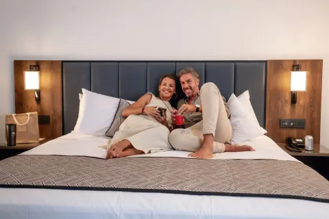 Guests relaxing on a Junior Suite Ocean View Elite Club king bed at Hotel Riu Palace Kukulkan.