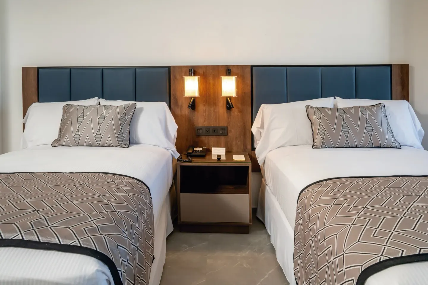 Two beds with shared nightstand in a Junior Suite at Hotel Riu Palace Kukulkan.