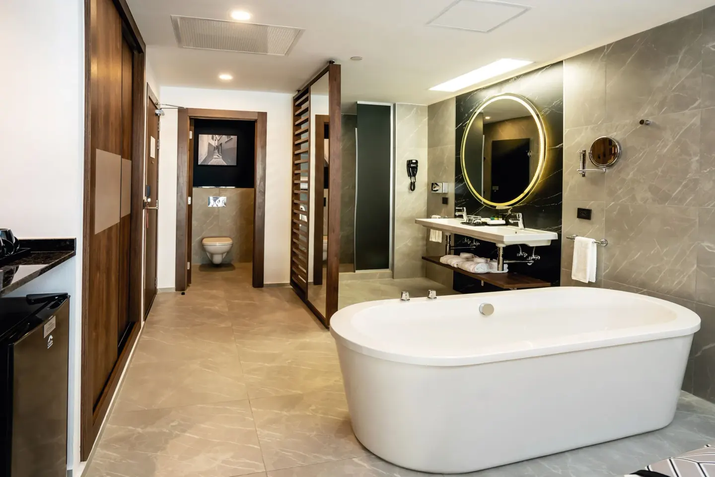 Junior Suite bathroom at Hotel Riu Palace Kukulkan with freestanding tub and round lit mirror.
