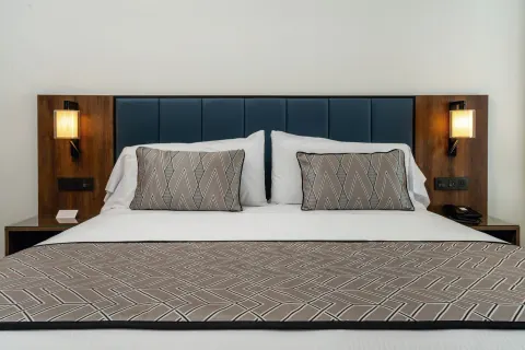 King bed in a Junior Suite at Hotel Riu Palace Kukulkan with blue headboard and wall lamps.