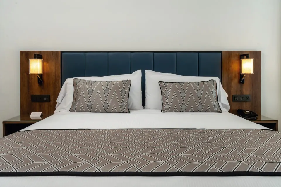King bed in a Junior Suite at Hotel Riu Palace Kukulkan with blue headboard and wall lamps.