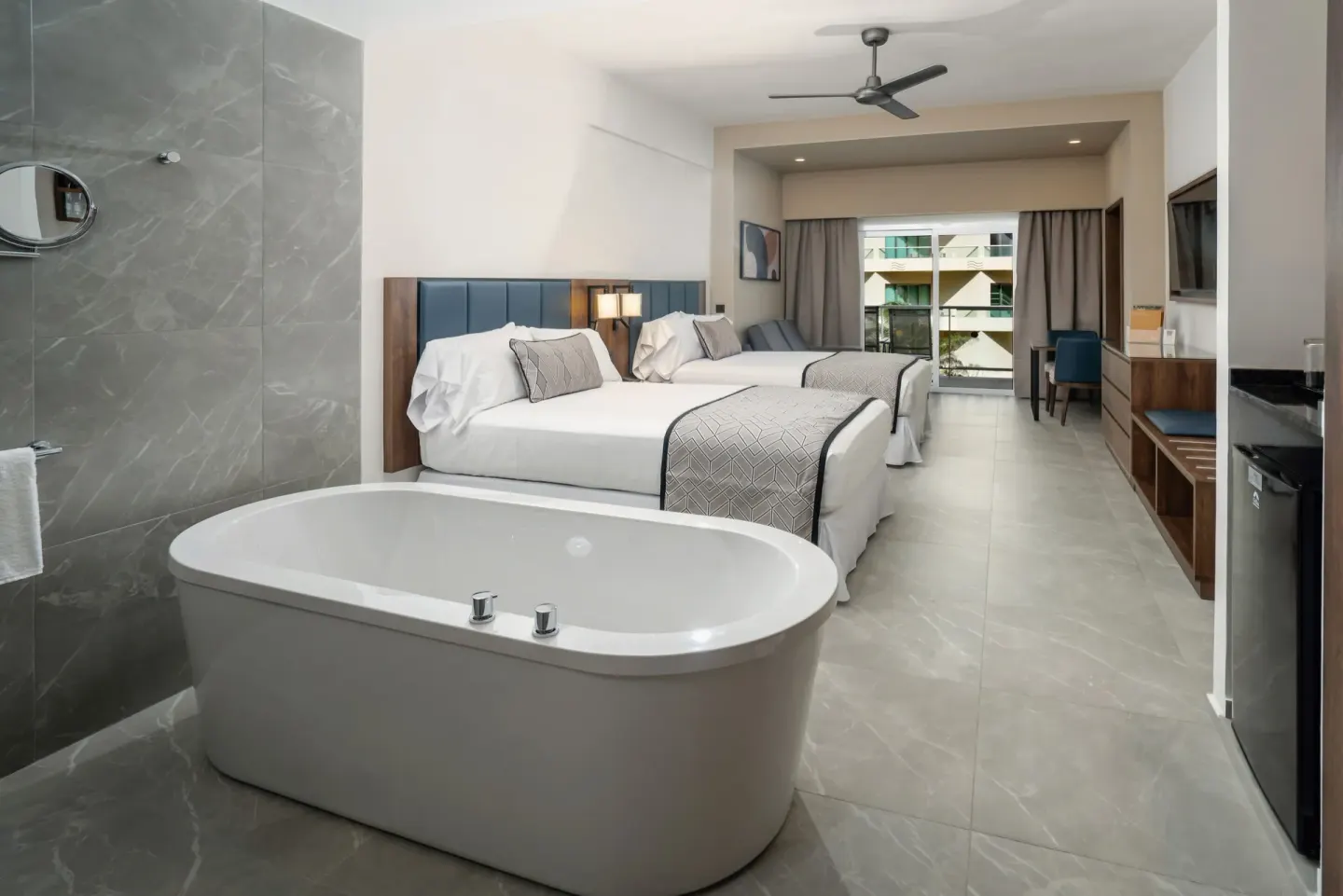 Junior Suite at Hotel Riu Palace Kukulkan with tub, two beds, balcony doors, and TV wall.
