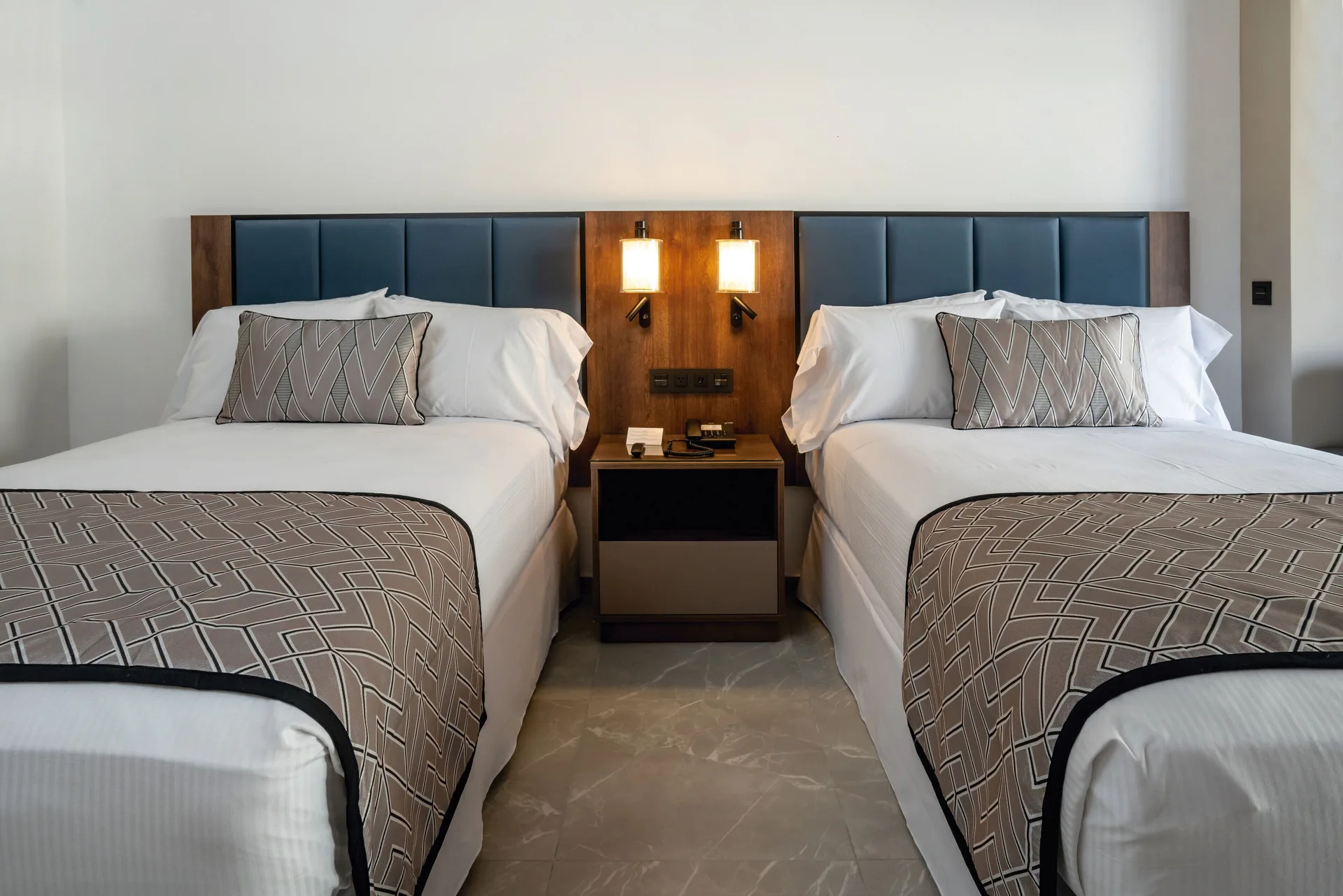 Two double beds in a Junior Suite at Hotel Riu Palace Kukulkan with lit bedside lamps.