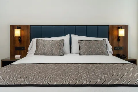 Junior Suite king bed with padded headboard and bedside lamps at Hotel Riu Palace Kukulkan.