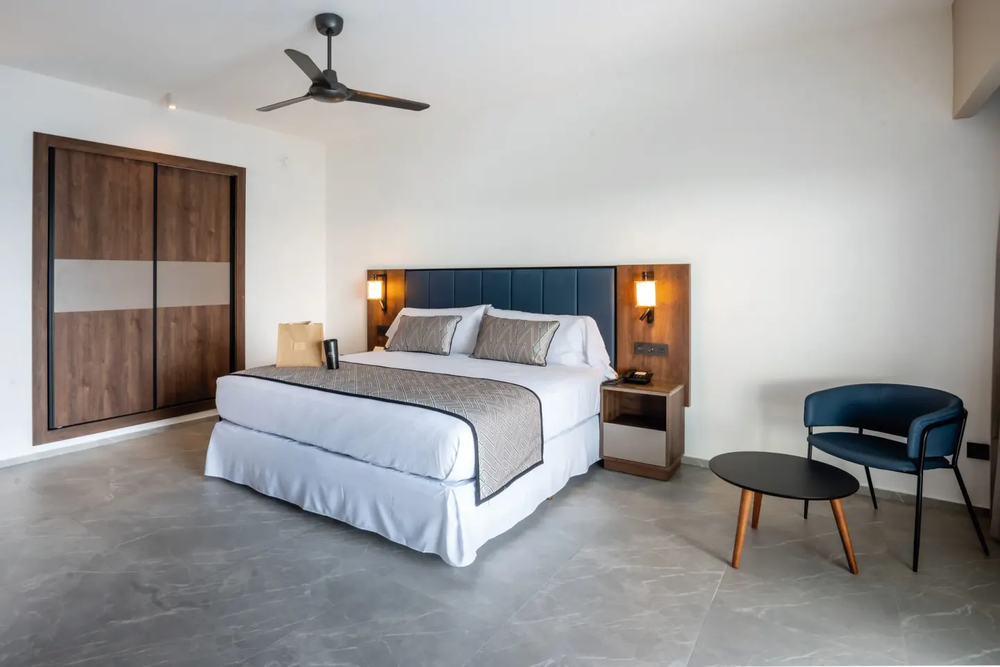 Suite Ocean View Elite Club king bed with wardrobe and chair at Hotel Riu Palace Kukulkan.