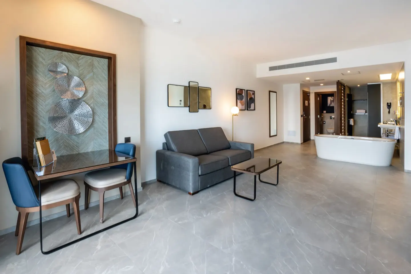 Suite Ocean View Elite Club sitting area with sofa, desk and tub at Hotel Riu Palace Kukulkan.
