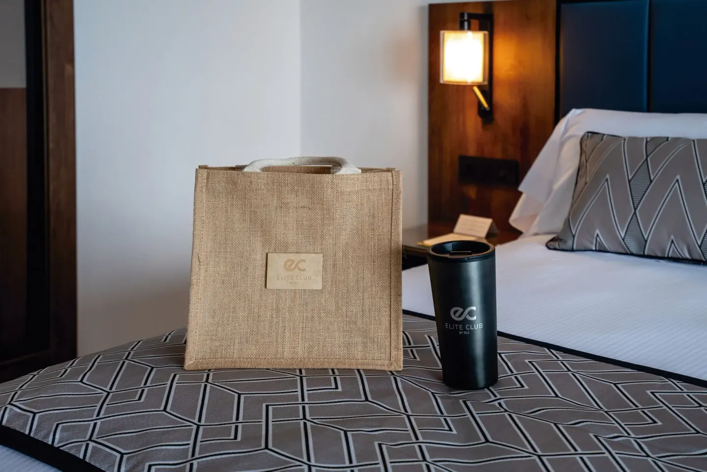 Suite Ocean View Elite Club welcome bag and tumbler on the bed at Hotel Riu Palace Kukulkan.