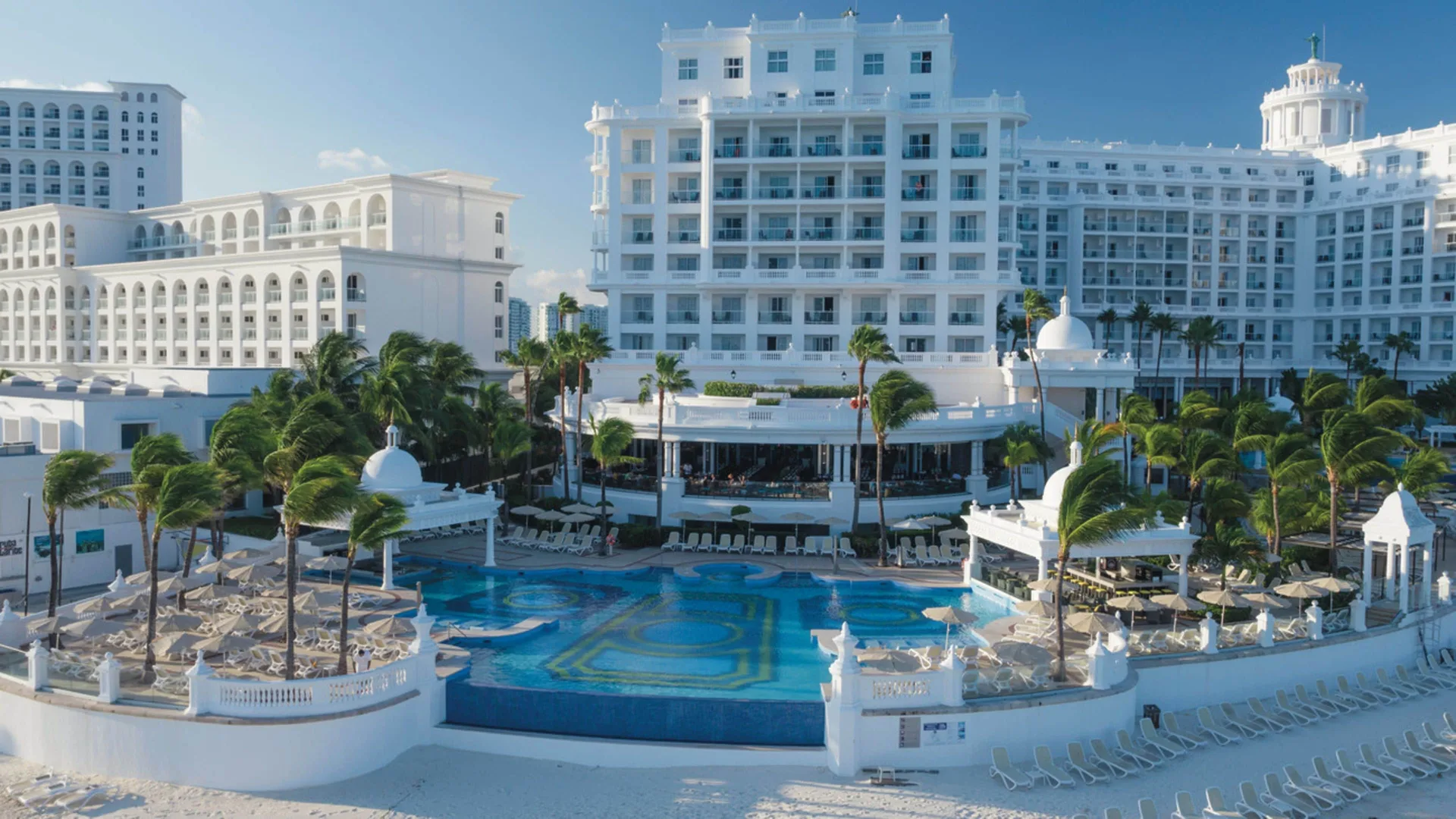 Pool courtyard and white resort buildings at Hotel Riu Palace Las Americas.