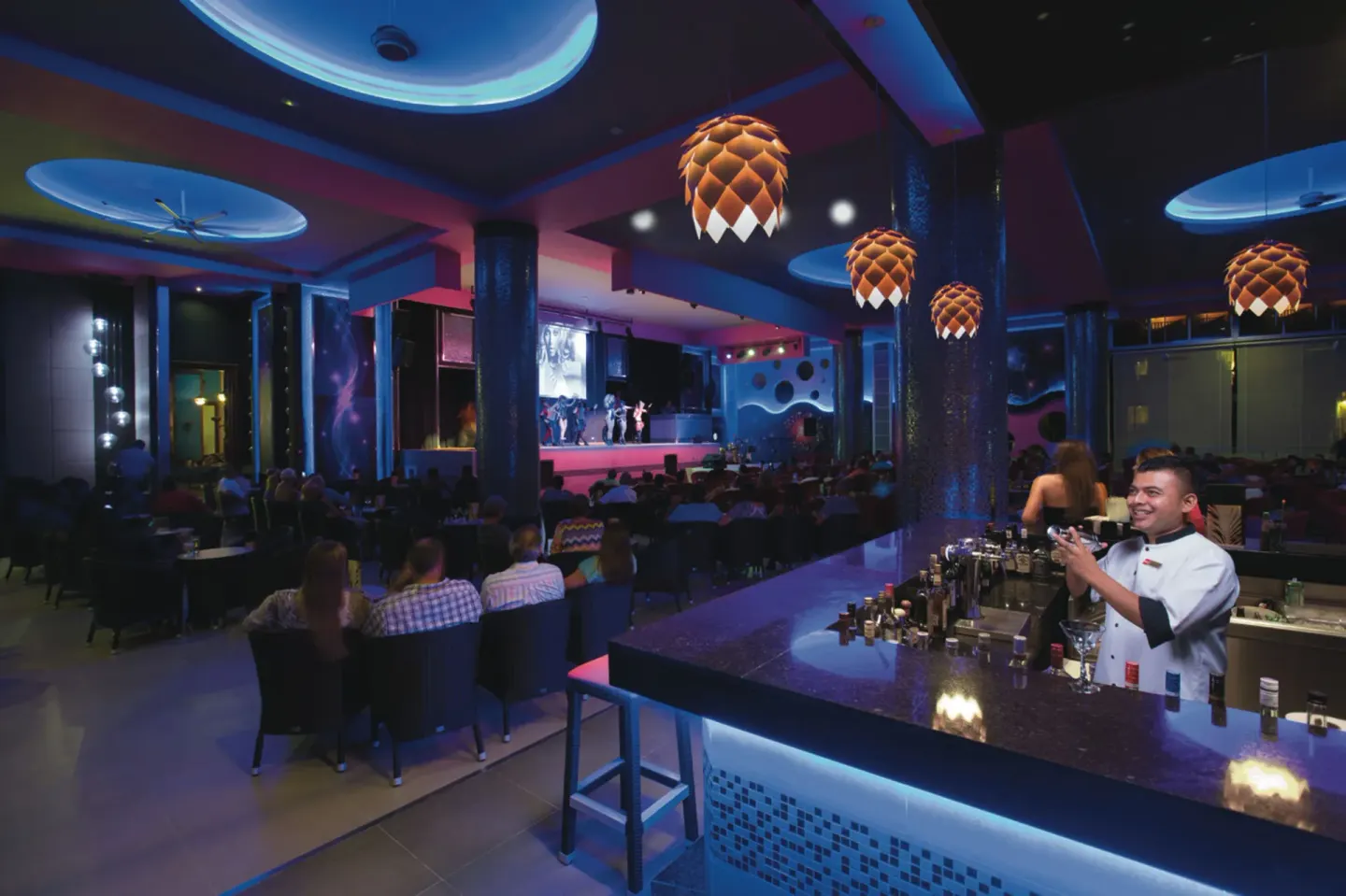 Bar lounge with bartender and stage show at Hotel Riu Palace Las Americas.