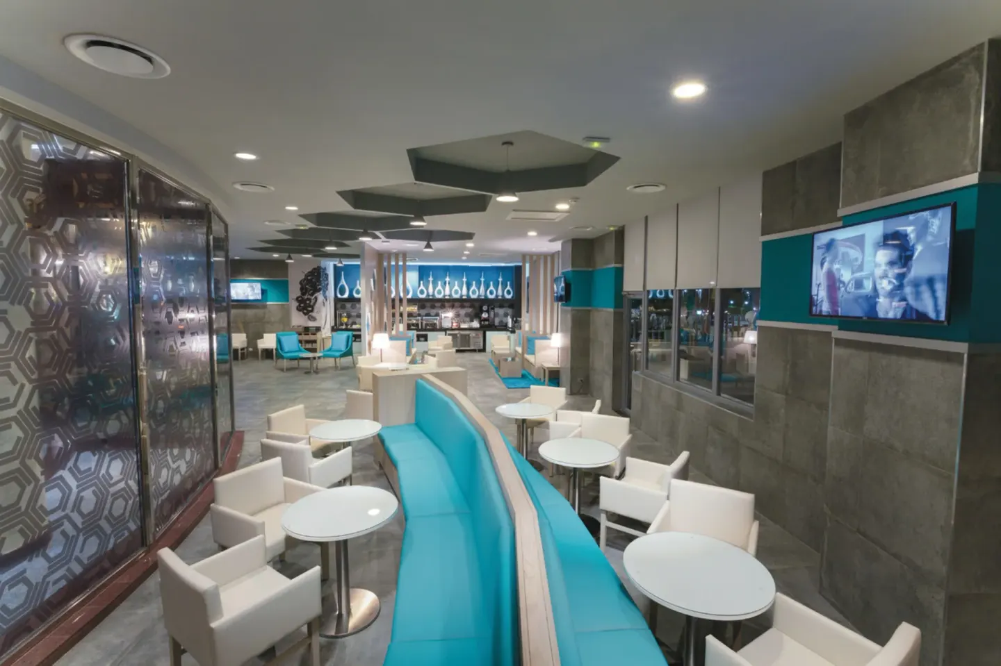 Modern cafe lounge with turquoise seating at Hotel Riu Palace Las Americas.