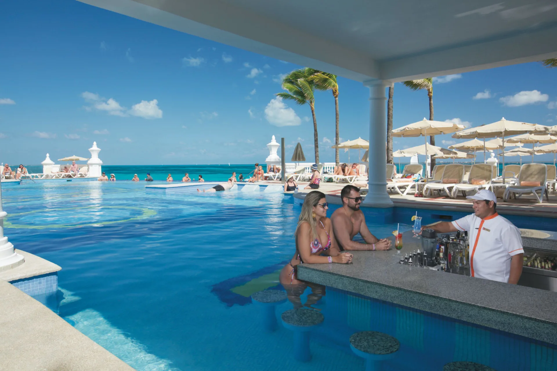Swim-up pool bar with ocean backdrop at Hotel Riu Palace Las Americas.