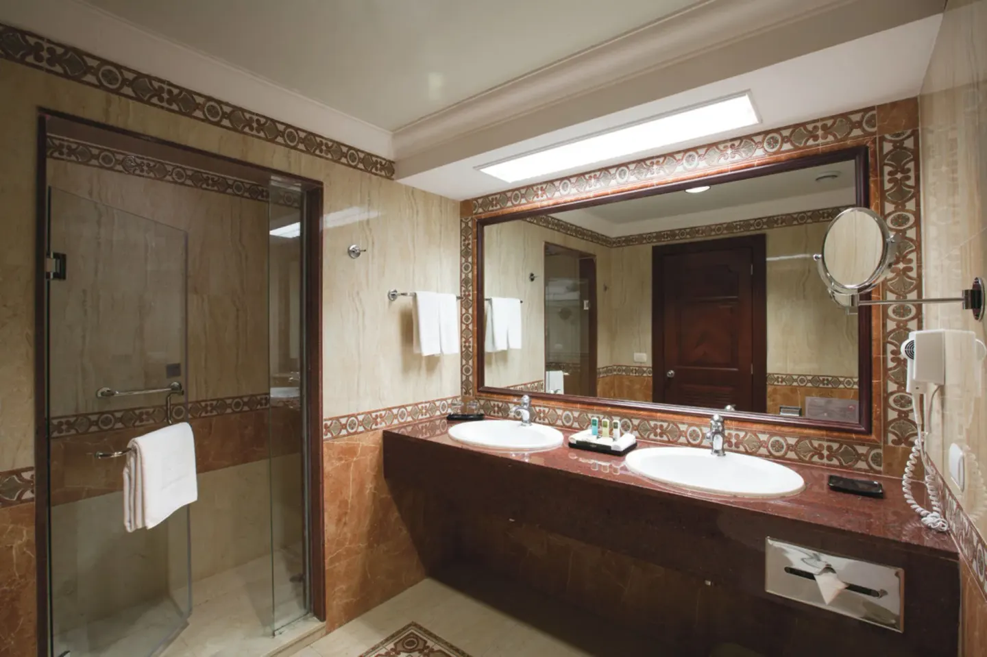 Junior Suite bathroom with double vanity and glass shower at Hotel Riu Palace Las Americas.