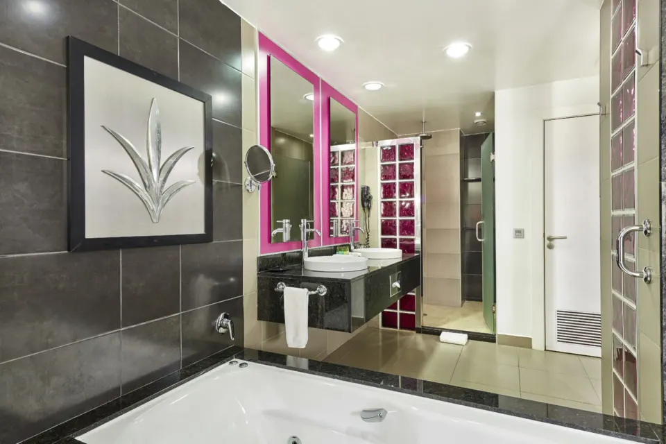 Bathroom with jetted tub and pink-accent mirror at Hotel Riu Palace Mexico