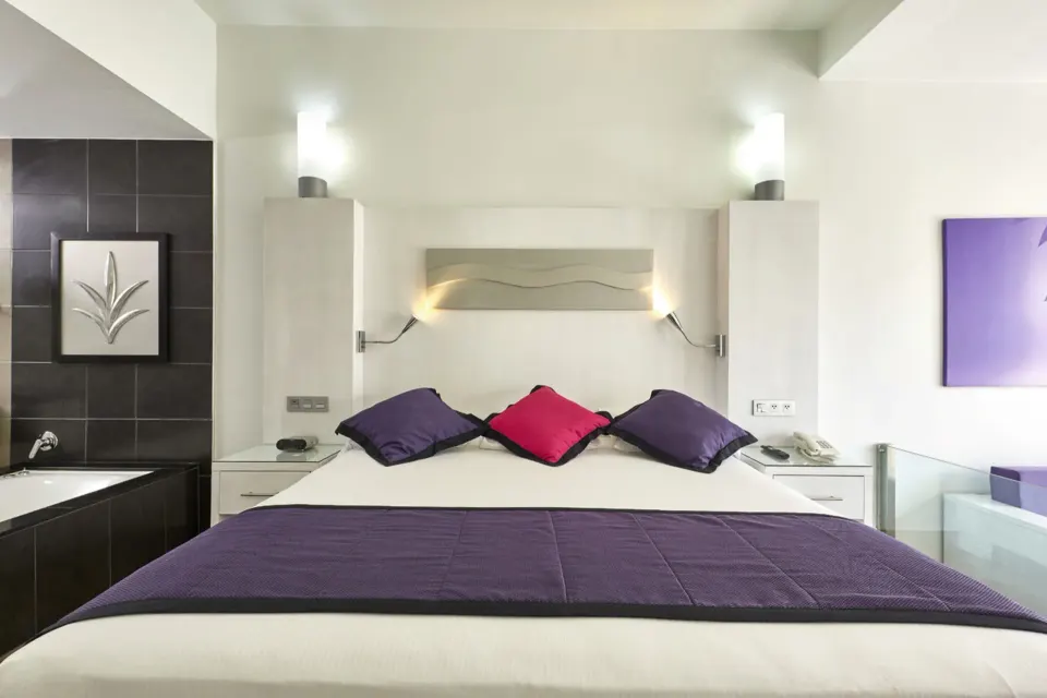 King bed with purple accents in a guest suite at Hotel Riu Palace Mexico