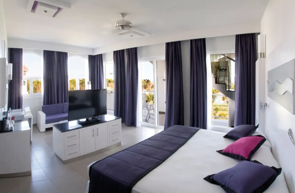 Spacious junior suite with king bed and separate seating at Hotel Riu Palace Mexico