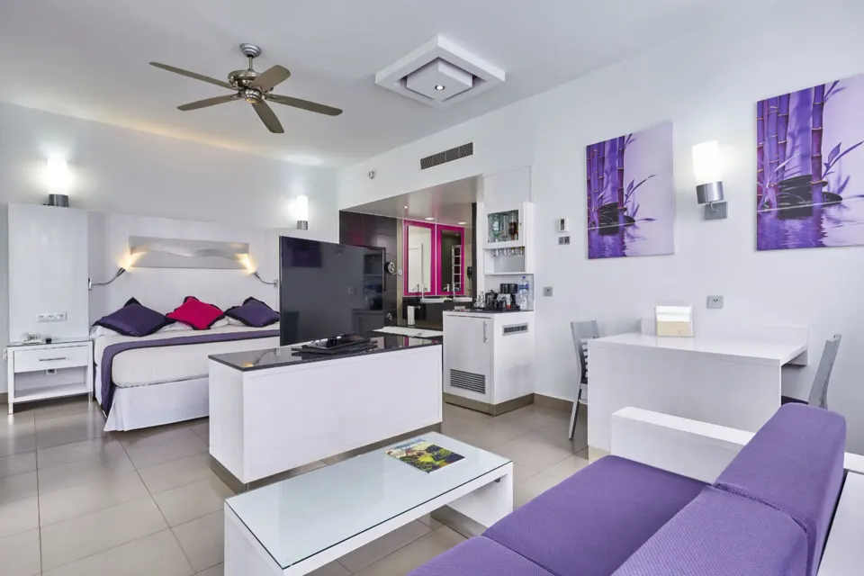 Junior suite open-plan living area and king bed at Hotel Riu Palace Mexico