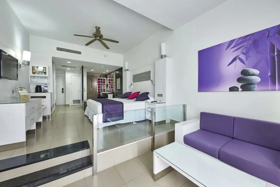 Long view of a junior suite showing bed, sofa and entrance at Hotel Riu Palace Mexico