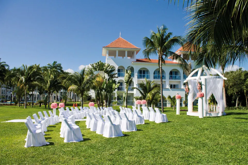 Outdoor wedding ceremony setup on the resort lawn with palm trees at Hotel Riu Palace Mexico