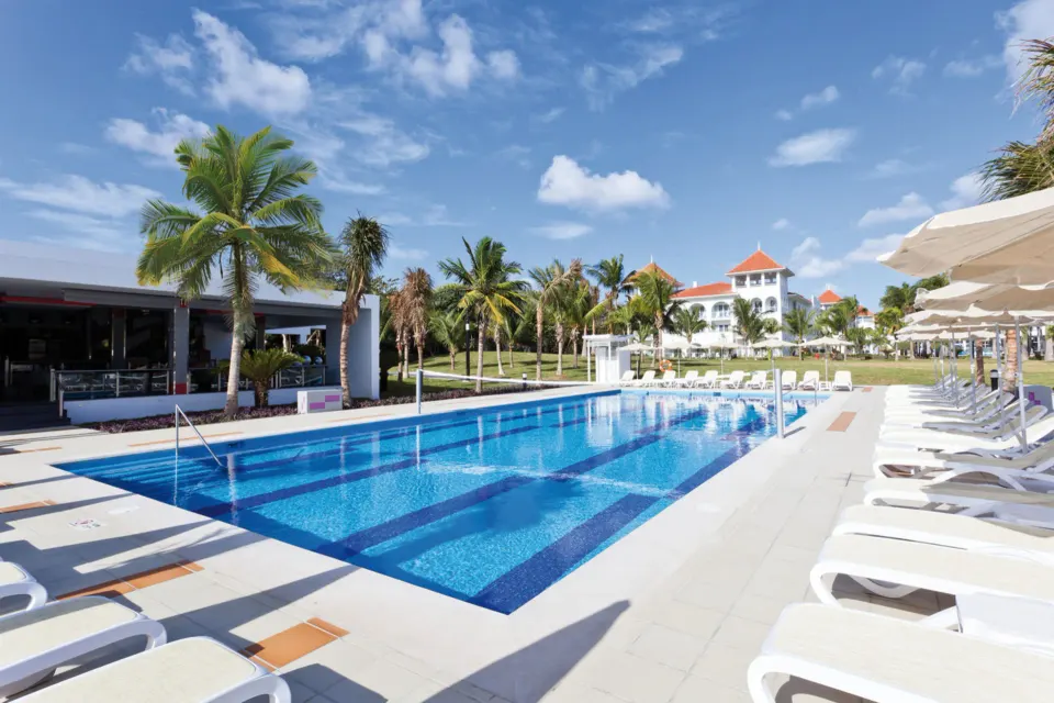 Main outdoor pool with rows of sunbeds and palms at Hotel Riu Palace Mexico