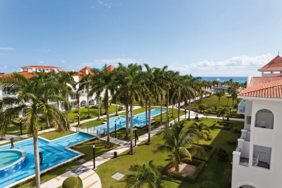 Palm-lined pools and gardens at Hotel Riu Palace Mexico with ocean beyond