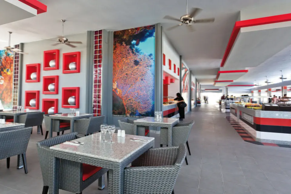 Bright buffet area with casual tables and decorative panels at Hotel Riu Palace Mexico