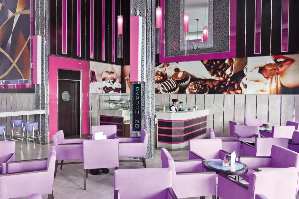 Bright pink and purple Capuchino café seating area at Hotel Riu Palace Mexico
