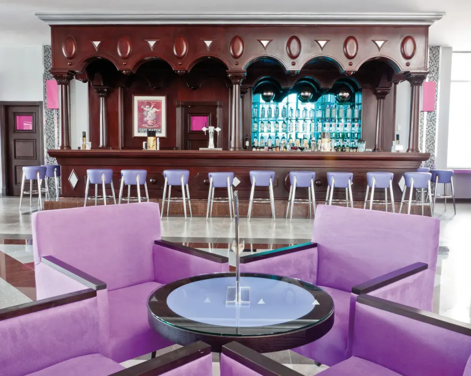 Wood-paneled lobby bar with purple seating area at Hotel Riu Palace Mexico