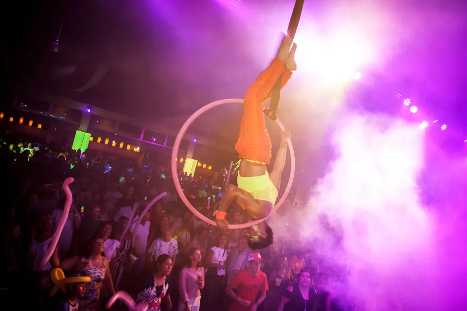 Aerial acrobat suspended in a hoop over a crowded night show at Hotel Riu Palace Mexico