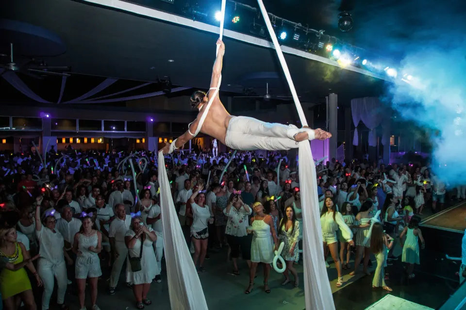 Aerial silk acrobat suspended above guests during a live show at Hotel Riu Palace Mexico