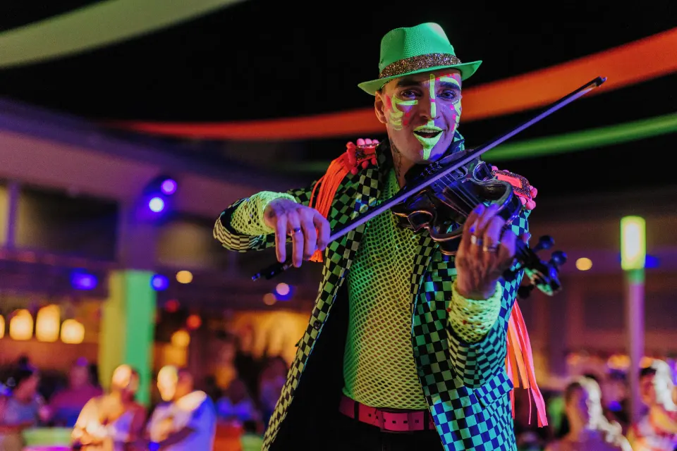 Violinist in colorful costume playing for guests at a nighttime event at Hotel Riu Palace Mexico