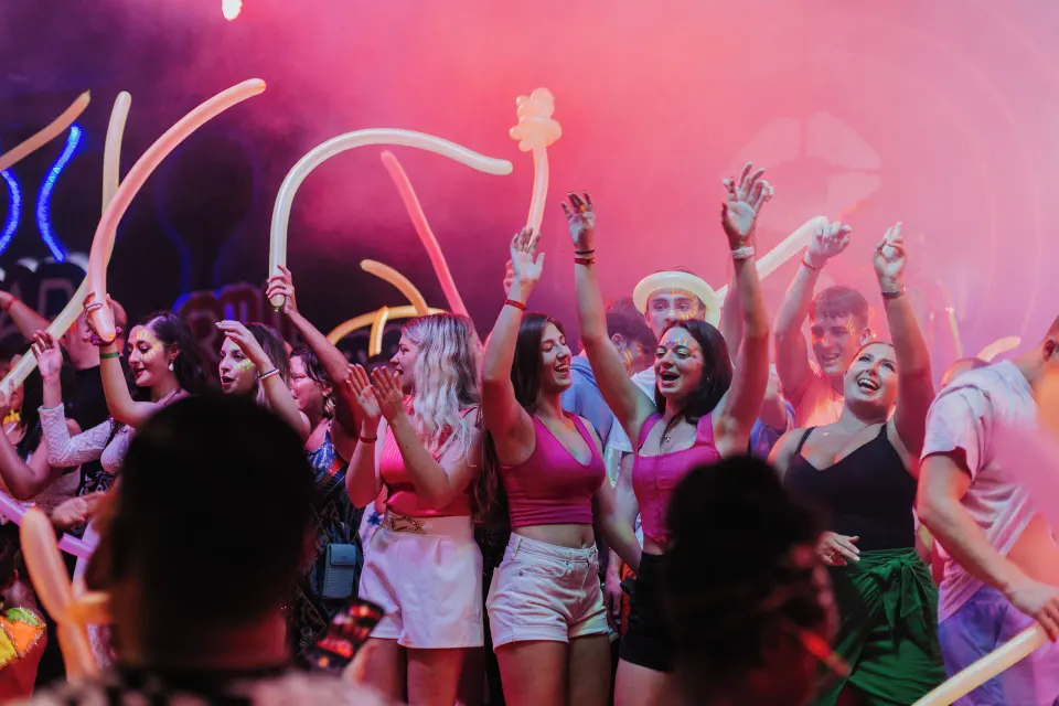 Group of guests dancing with glow stick balloons at a lively resort party at Hotel Riu Palace Mexico