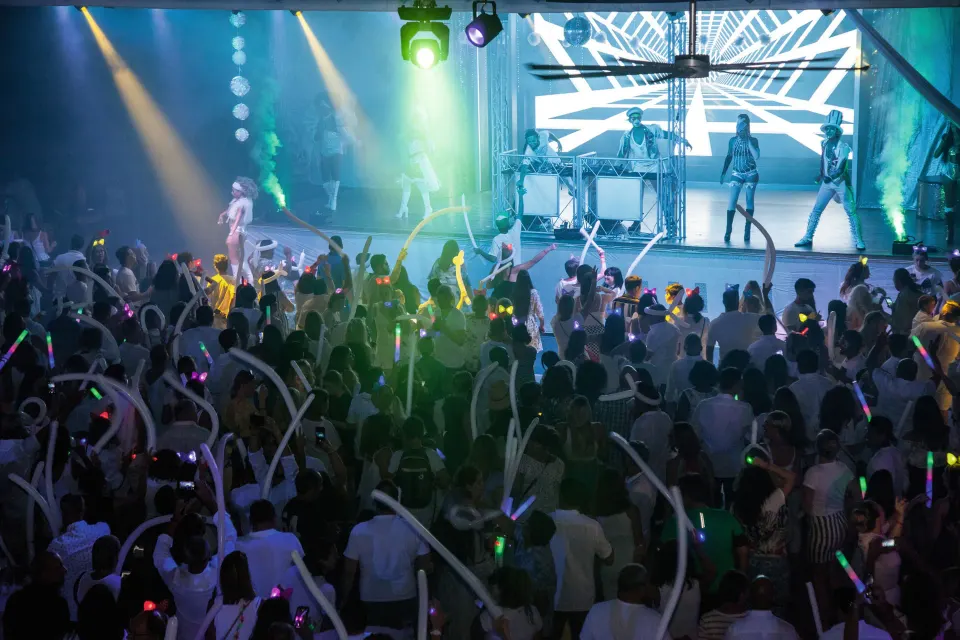 Crowded dance floor with performers on an illuminated stage at Hotel Riu Palace Mexico