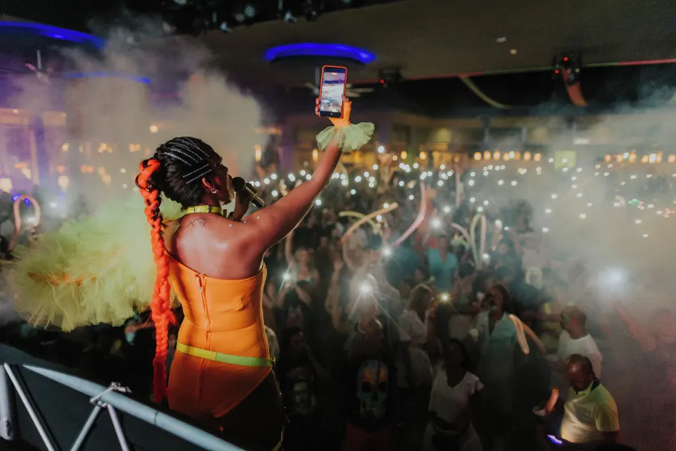 Performer taking a selfie from the stage while the crowd lights up phones at Hotel Riu Palace Mexico