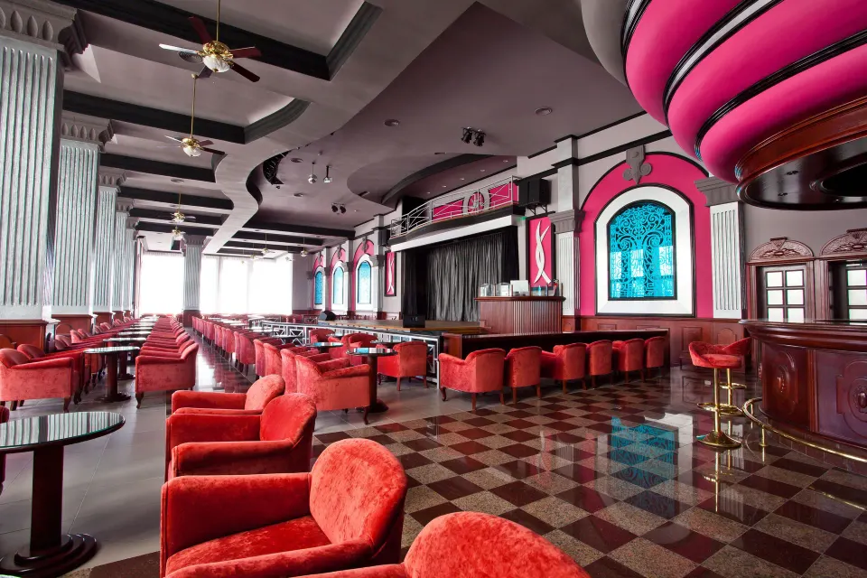Large lounge with stage and red upholstered chairs at Hotel Riu Palace Mexico
