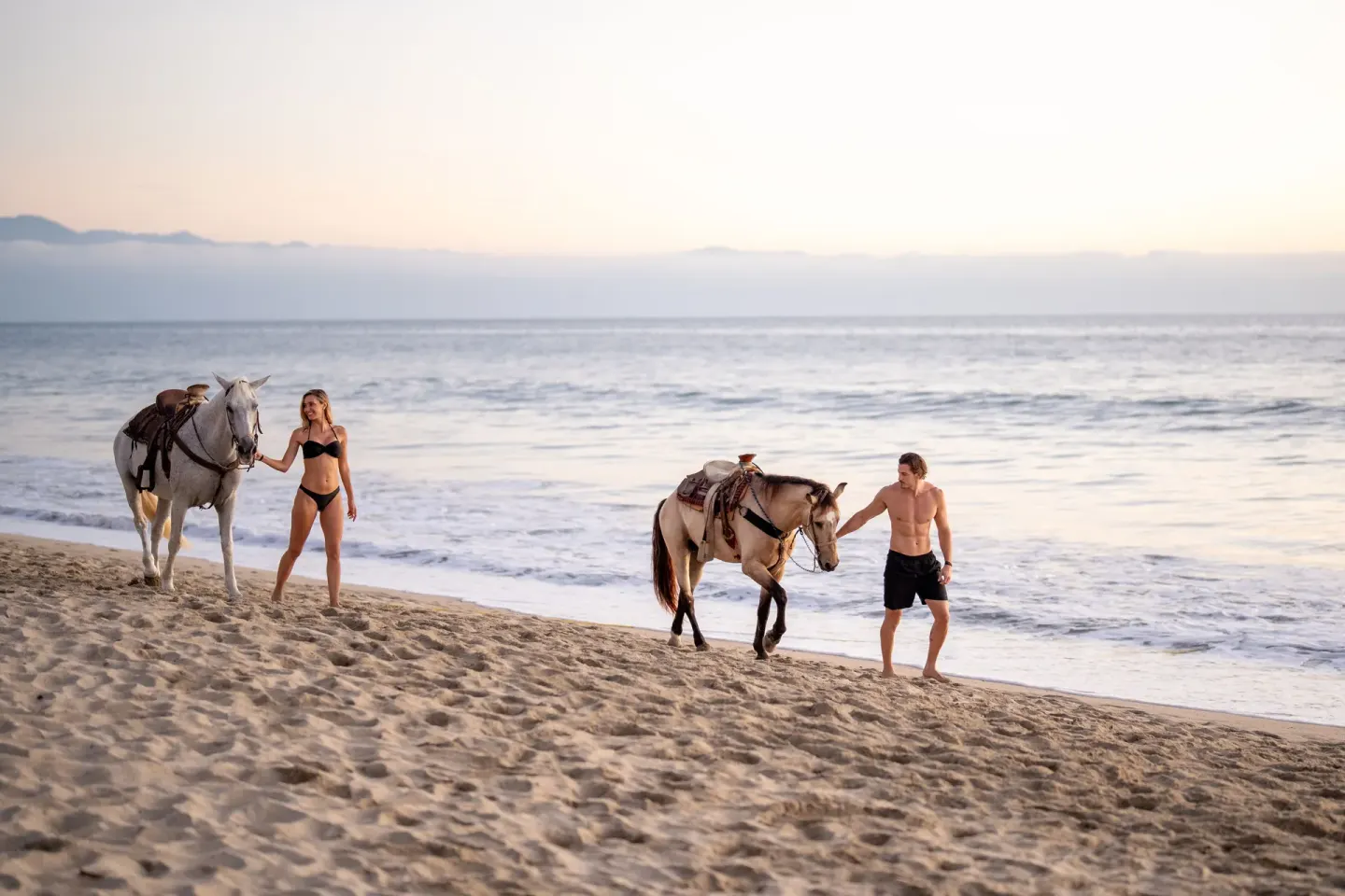 Guests walk horses beside the surf at Hotel Riu Palace Pacifico.