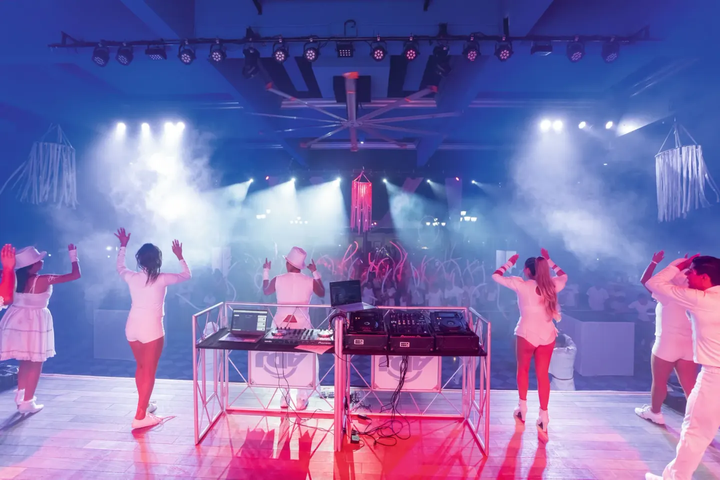 Performers and a DJ face a crowd under stage lights at Hotel Riu Palace Pacifico.